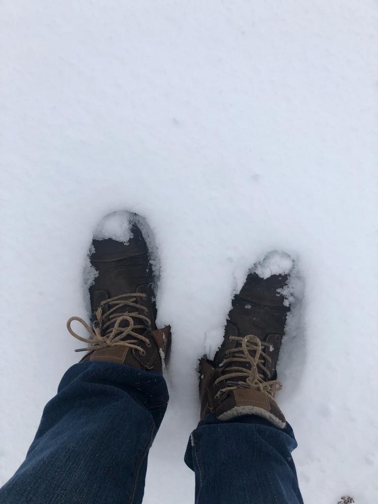 Två ben och snötäckta kängor som går i snön. Foto.